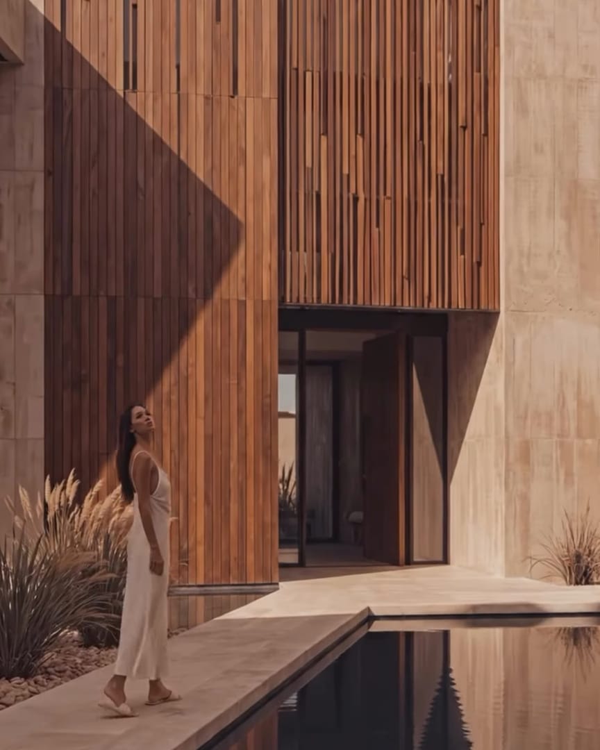 From Shriram Properties' teaser: a timber facade beside a reflecting pool