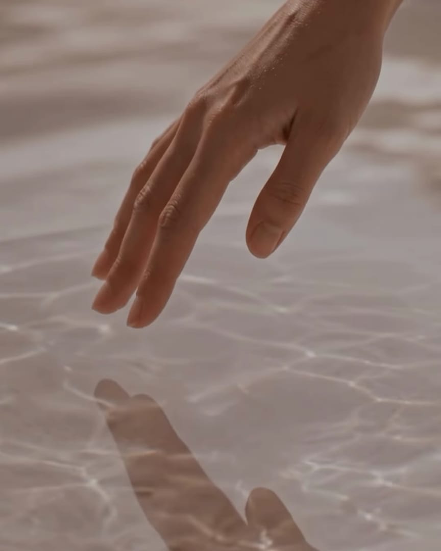 A hand touching still pool water